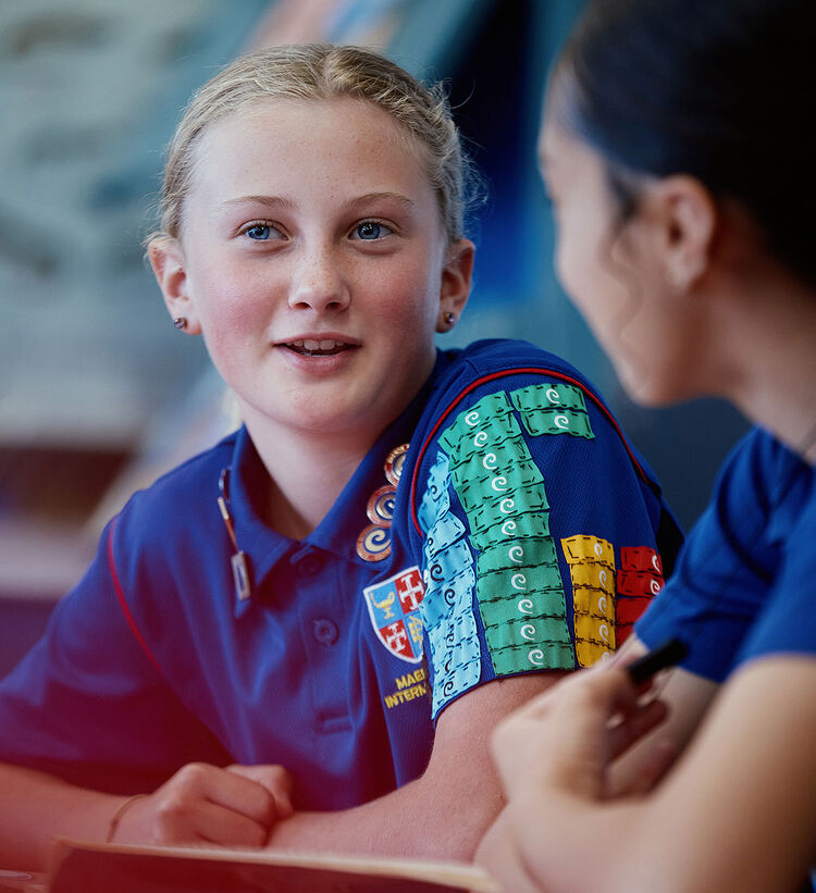 Student in Maeroa Intermediate uniform talking with a classmate during class.