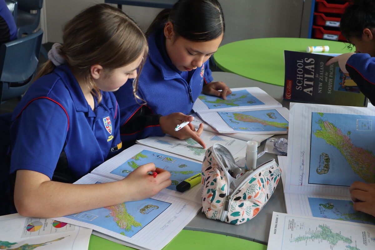 Two students studying maps and atlases during a geography lesson.